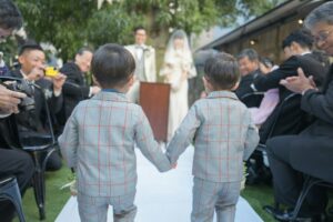 Children stand beside a couple during a wedding ceremony as an adult guides a young ring bearer.